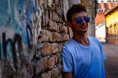 Young man posing beside a rustic wall Stock Photos