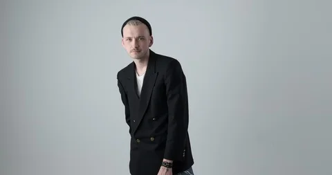 Young man posing in black blazer and knit hat over white background Video stock 105179426