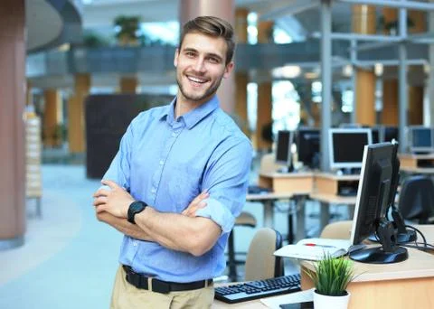 Young man posing confident and positive in professional workplace office. Stock Photos