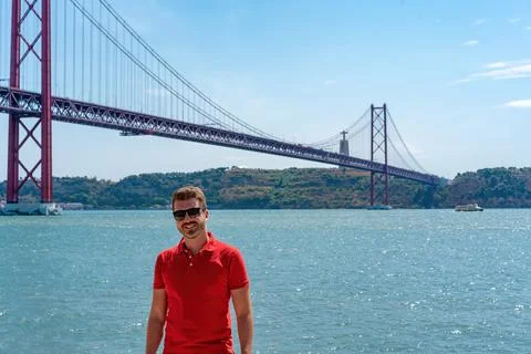 Young man posing in front a famous steel bridge in Lisbon Foto stock