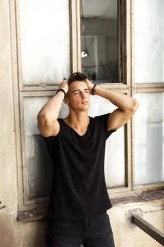 Young man posing with hands in hair by window Foto stock