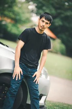 Young Man Posing Next to Car in a Natural Outdoor Setting Foto stock