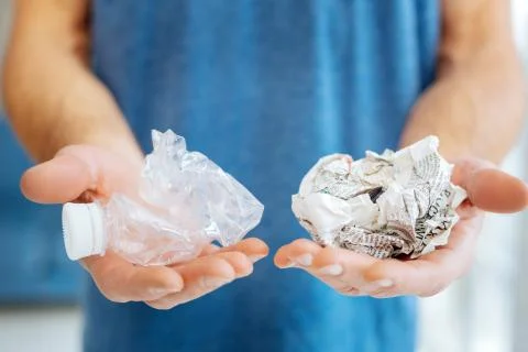 Young man posing with plastic bottle and crumpled newspaper Stock Photos