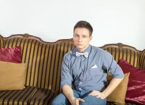 Young man posing seated on a sofa at home Stock Photos