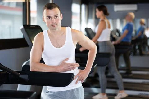Young man posing by treadmill in gym Stock Photos