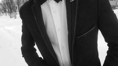 Young man posing in a tuxedo in the winter against the white snow,shot in retro Stock Footage 85069711