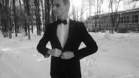 Young man posing in a tuxedo in the winter against the white snow,shot in retro Video stock 85070602