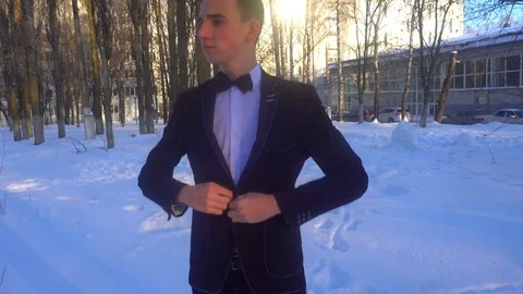 Young man posing in a tuxedo in the winter against the white snow,shot in retro Stock Footage 85138124