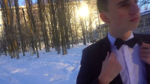 Young man posing in a tuxedo in the winter against the white snow,shot in retro Stock Footage 85139418