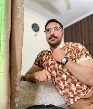 Young man posing while looking out from room window wearing a smart watch Stock Photos