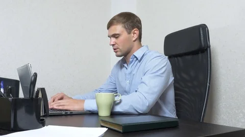 A young man poured tea onto a laptop. works in the office. Stock Footage 87956227