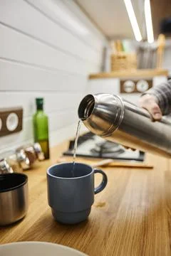 Young man pouring hot coffee into cup from thermos travelling with trailer van Stock Photos