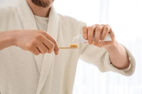 Young man pouring tooth paste onto brush in bathroom, closeup Stock Photos