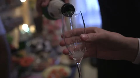 A young man pours sparkling white wine in the glass stylish guy in a white shirt Stock Footage