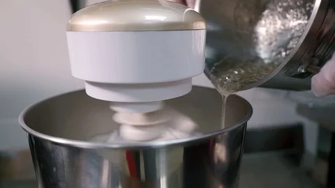 Young man pours sugar mixture into bowl with working mixer in kitchen. Stock Footage 83977269