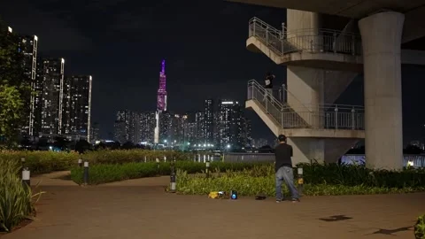 A young man practices breakdance moves in a riverside park against the glowing Stock Footage 332988776