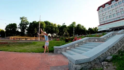 A young man practices a handstand near the Sadko Fountain in Sumy, Ukraine Stock Footage 319072391