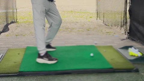 A young man practices his swing and hits a ball at an outdoor driving range. Video stock 344556406
