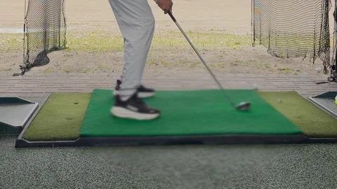 A young man practices his swing and hits a ball at an outdoor driving range. Video stock 344556477