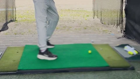 A young man practices his swing and hits a ball at an outdoor driving range.  Video stock 344556961