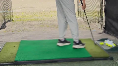 A young man practices his swing and hits a ball at an outdoor driving range.  Video stock 344557225