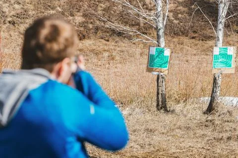 Young man practices shooting at two cardboard targets in a field Stock Photos