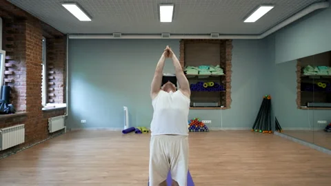 Young man practices yoga in VR glasses standing on blue mat Stock Footage 208037538