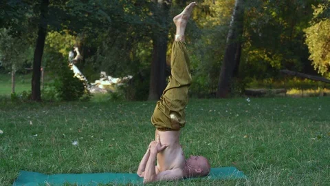 Young Man Practicing Asanas of Yoga Exercises the Shoulder Stance Exercise in Stock Footage 85801682
