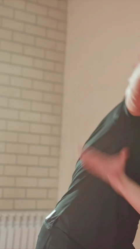 Young man practicing boxing and martial arts indoors against brick wall with Stock Footage 345547819