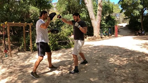 Young man practicing boxing with gloves personal training at a park Stock Footage 139157568