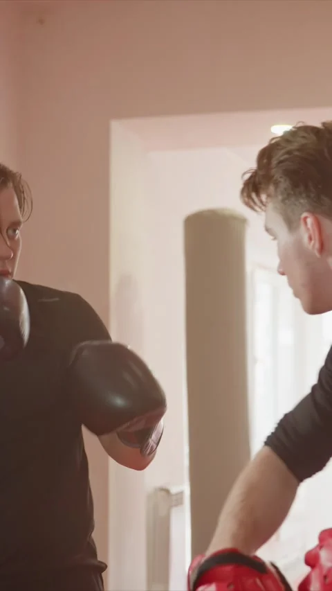 Young man practicing boxing indoors with gloves and targets with training Stock Footage 345548761