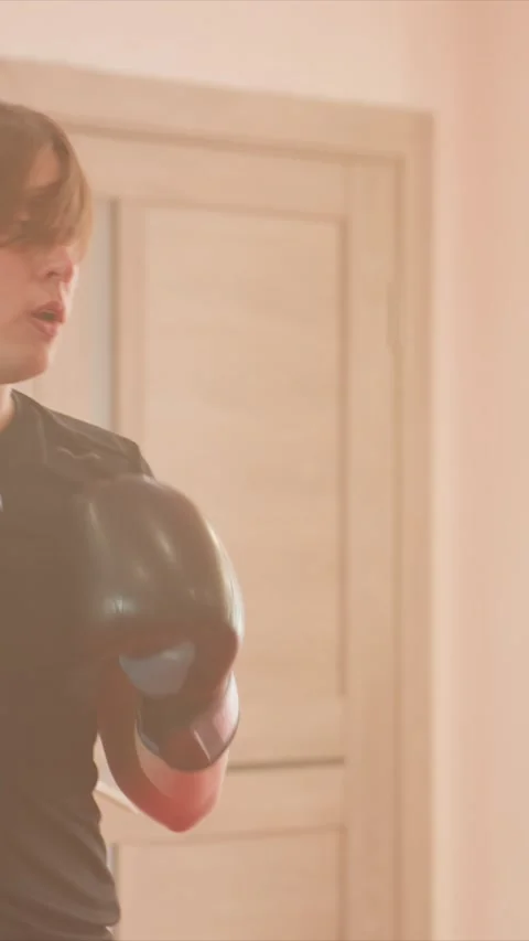 Young man practicing boxing indoors with punches and movements in warm lighting Stock Footage 345549207