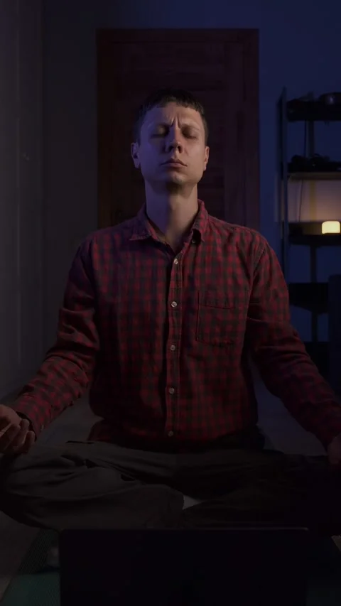 Young man practicing breathwork with laptop at home, evening atmosphere, healthy Stock Footage 316892578