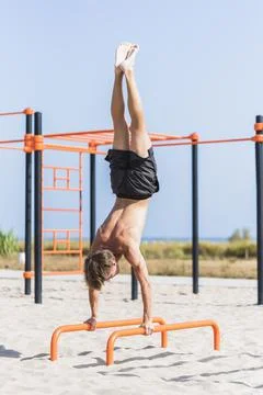Young man practicing calisthenics on parallel bars. Stock Photos