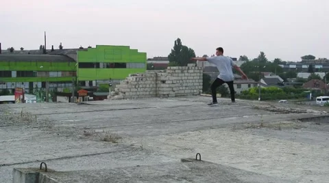 Young man practicing flips and jumps at the roof of building. Stock Footage 67316076