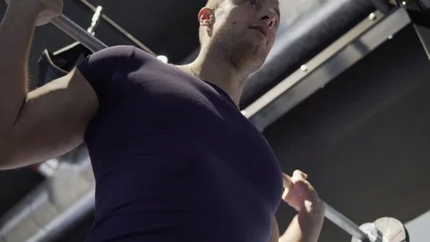 A young man is practicing at the gym. He crouches with a barbell. 4K Stock Footage 73779807