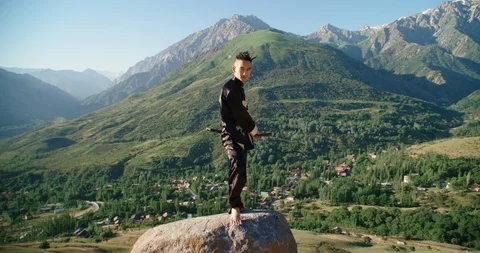 Young man practicing kung fu with sword. Tai Chi at the top of the mountain Video stock 116716102