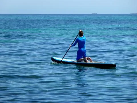 Young man practicing paddle on the beach with calm sea Stock Photos