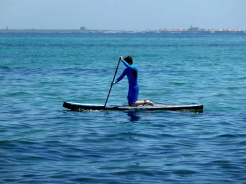 Young man practicing paddle on the beach with calm sea Stock Photos