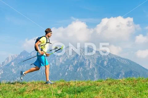 Young man practicing physical activity mountain and running with sticks Stock Photos