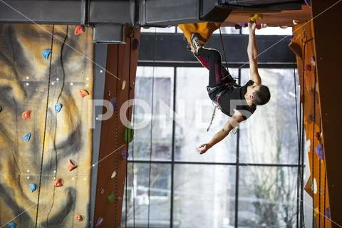 Young man practicing rock-climbing in climbing gym Stock Photos