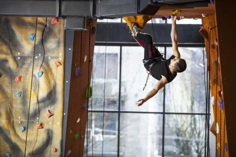 Young man practicing rock-climbing in climbing gym Stock Photos