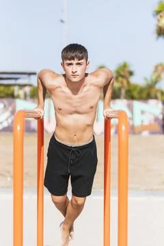 Young man practicing triceps exercices on parallel bars. Stock Photos