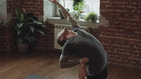 Young man practicing yoga and stretching in studio with brick wall Stock Footage 116100162