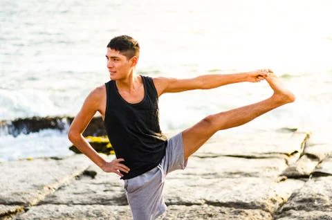Young man practicing yoga, doing Parivrtta Utthita Hasta Padangusthasana Stock Photos