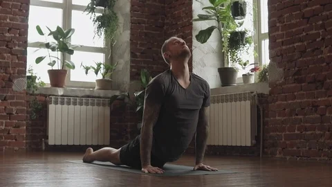Young man practicing yoga in studio. Guy doing an asana on black mat indoors Video stock 112734193