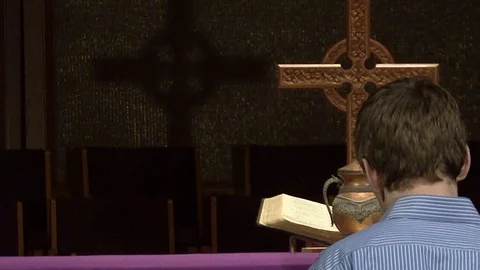 Young Man Praying In Front of Cremated Ashes in Urn at Front of Altar in Church Stock Footage 125284226