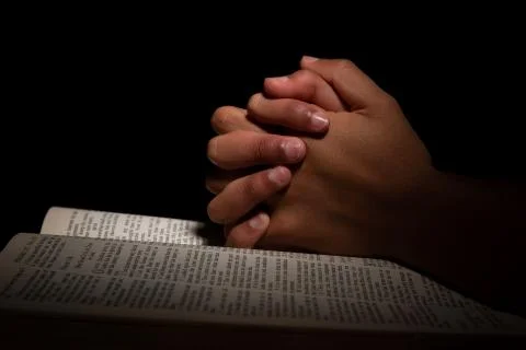 Young Man Praying with Hands on Top of the Bible. 스톡 사진