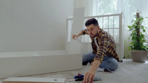 Young man prepares the future child's room by assembling the furniture. A bright Stock Footage 281979136