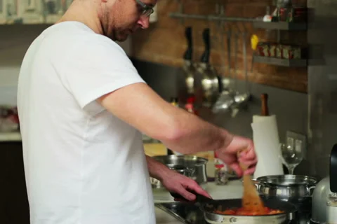 Young man preparing and tasting dinner in his kitchen Stockbeeldmateriaal 36658141